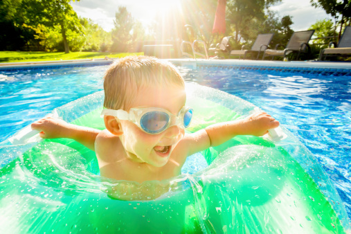 A little boy in a pool with a water toy