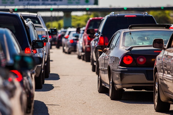A congested highway filled with cars and SUVs stuck in heavy traffic under bright sunlight.