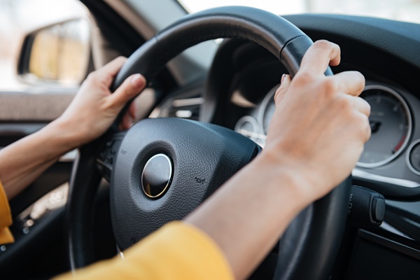 Close-up of a teen girl's hands on the steering wheel of a car as she drives down a Florida road.
