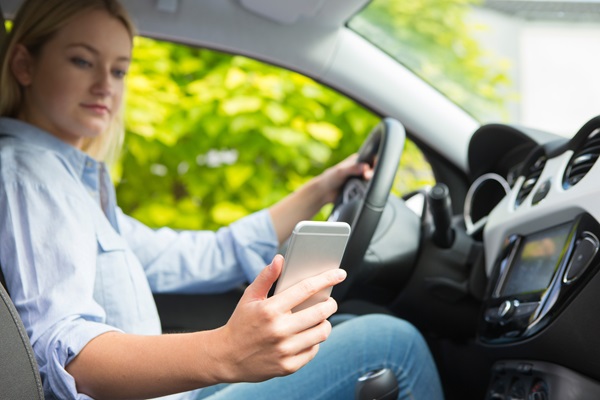 A driver holding a smartphone while operating a vehicle, a common form of negligence that contributes to the high rate of distracted driving accidents throughout Central Florida.